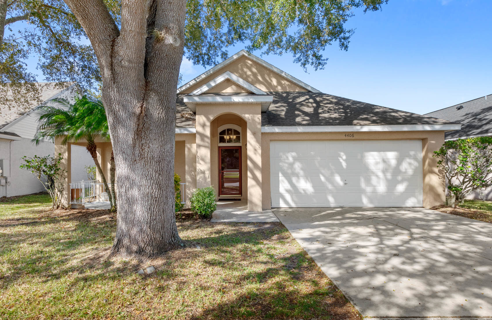 front of one story home with yellow paint and large tree trunk